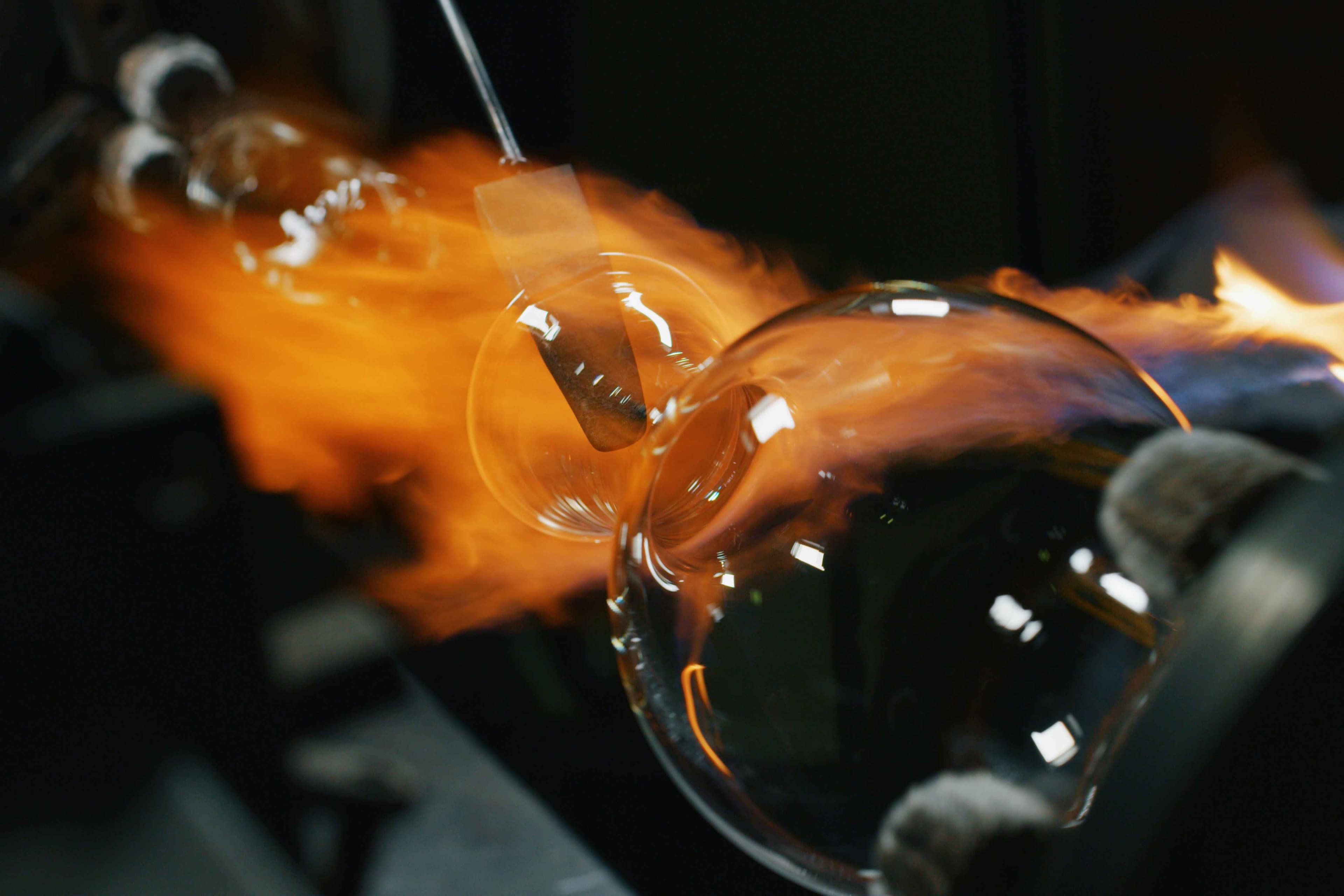 Close up macro of glass blower working with flame on a handmade wine glass from precious crystal in a workshop. Shot in 8K. Concept of handmade,high quality, artisan, made in Italy,glass blowing
